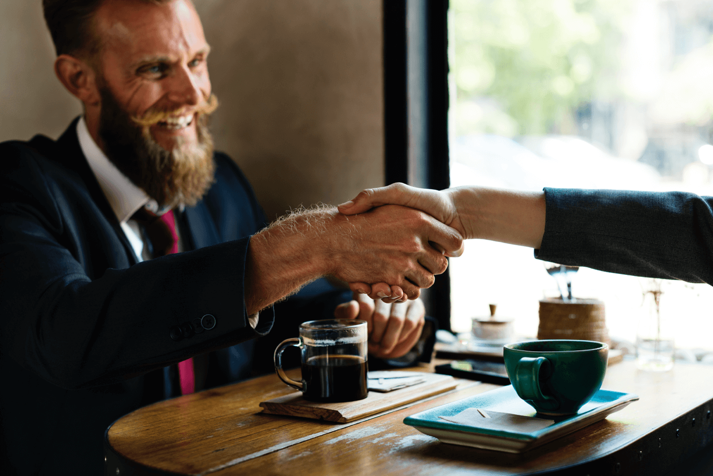 a man with a beard shaking hand with someone at the desk