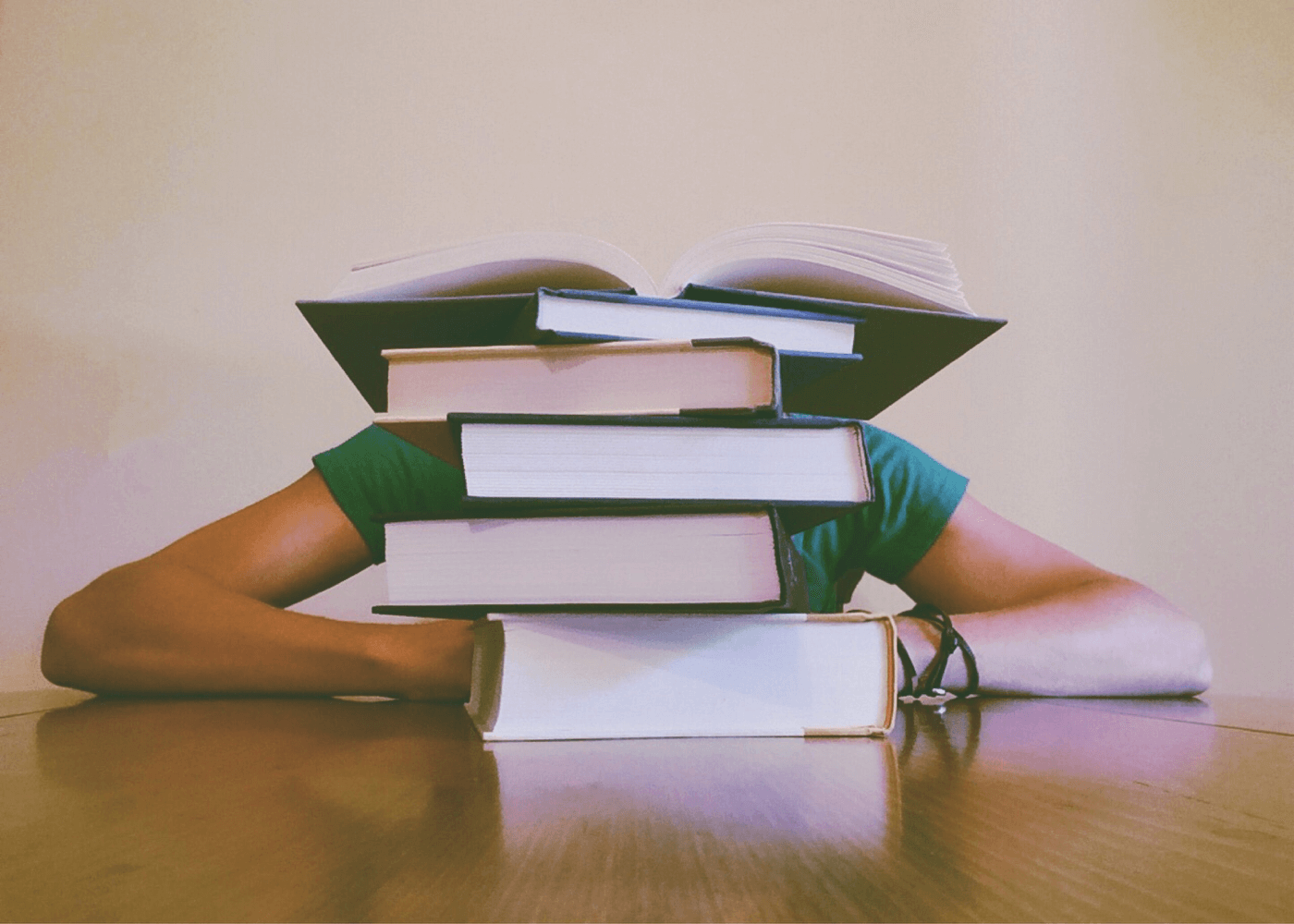 a pile of books and a person behind